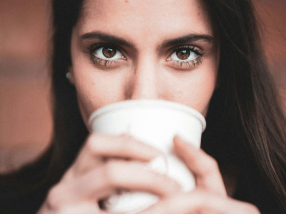 Une jeune femme buvant un café sans lunettes pour illustrer les Bénéfices d’une Opération Réfractive : Une Vision Transformée au Quotidien